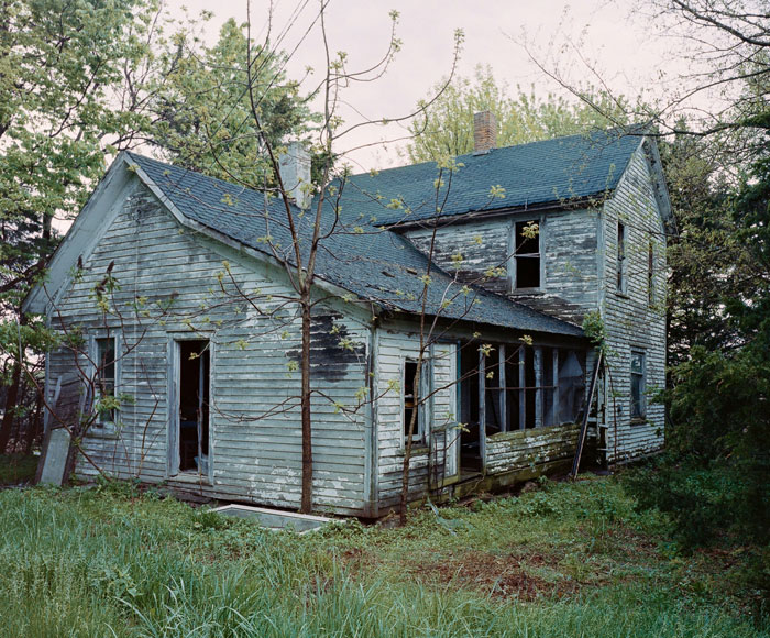 Abandoned creepy house surrounded by overgrown vegetation, evoking terrifying urban explorers moments in deserted locations.