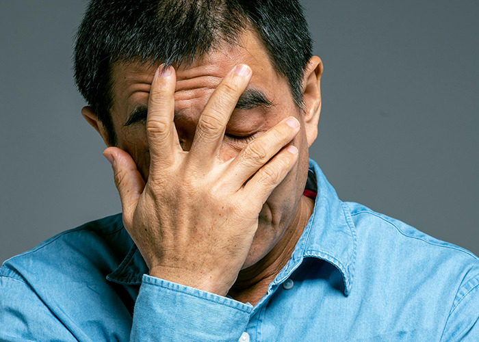 Man in blue shirt covering face with hand, expressing regret after receiving horrible gifts shared by 91 people.