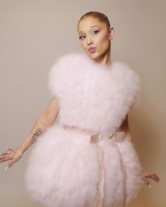 Ariana Grande posing in a fluffy light pink dress, showcasing her style amid home wrecking discussions.