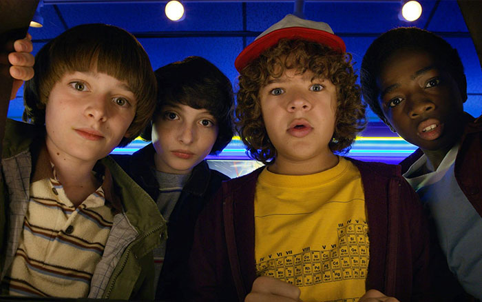 Four Stranger Things kids looking surprised under neon lights, reflecting the creators&rsquo; cryptic warning before final episodes.
