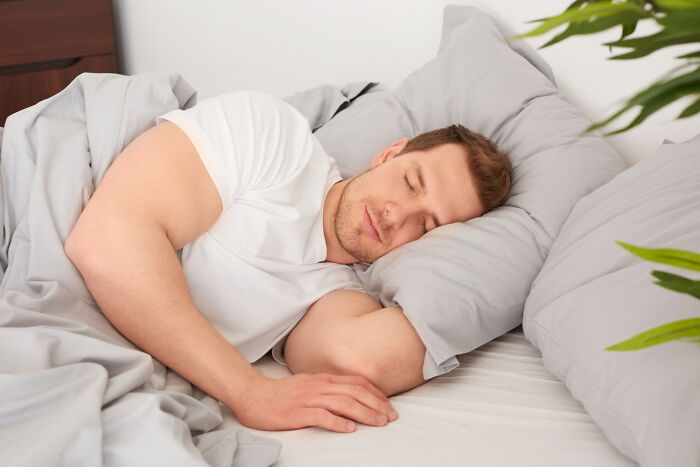 Man sleeping peacefully on bed, illustrating surprising habits and secrets people discover about their partner after moving in.
