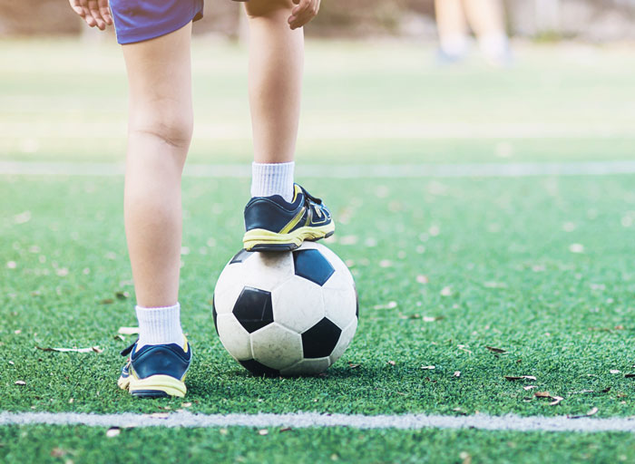 Child in blue shorts balancing foot on a soccer ball on green field illustrating wildest family drama online
