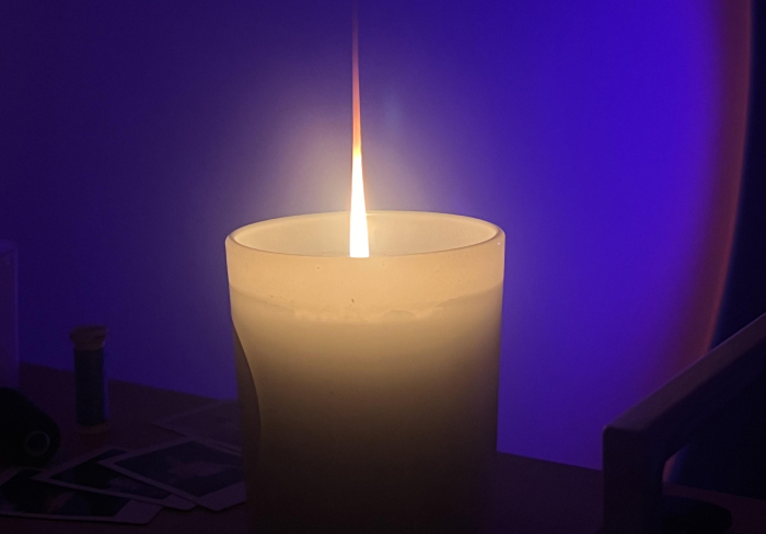 Lit candle in a dark room creating an eerie atmosphere for the best scary games to play with friends IRL.