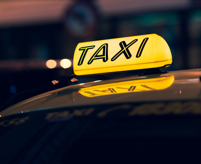 Yellow taxi sign illuminated at night, representing a street scene related to instant karma moments.