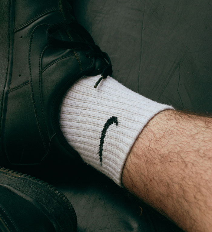 Close-up of a person wearing black shoes and white Nike socks, illustrating a casual Oscar-worthy performance moment.