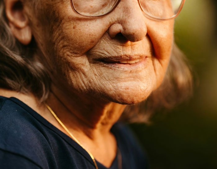 Close-up of an elderly woman smiling gently, illustrating funny patients comments breaking the serious vibe in hospitals.