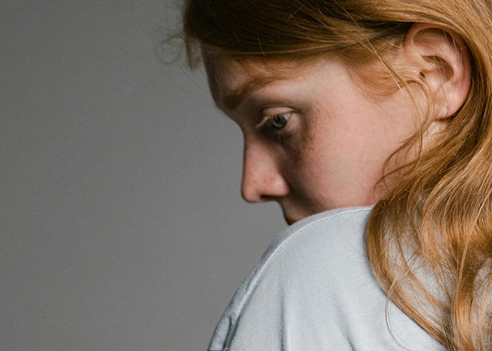 Young woman looking down pensively, conveying emotions related to bizarre events that creep people out.