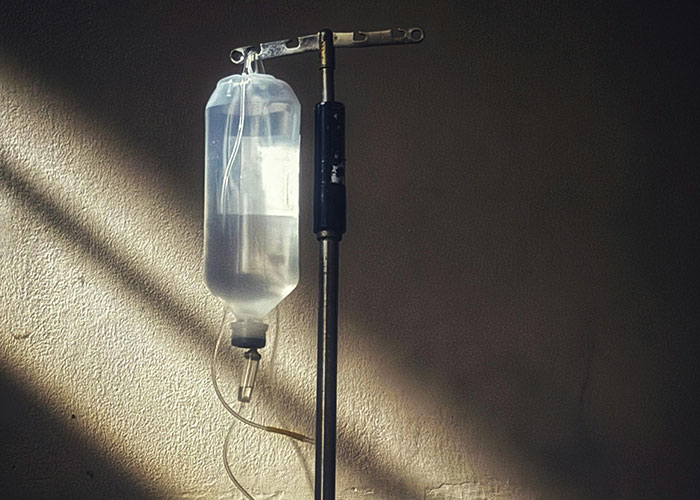 Intravenous drip bag hanging on metal stand against a dim wall, evoking terrifying things found online.