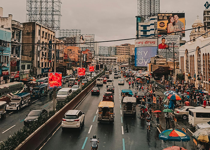 Busy urban street in one of the worst cities worldwide, crowded with vehicles and pedestrians under rainy weather conditions.