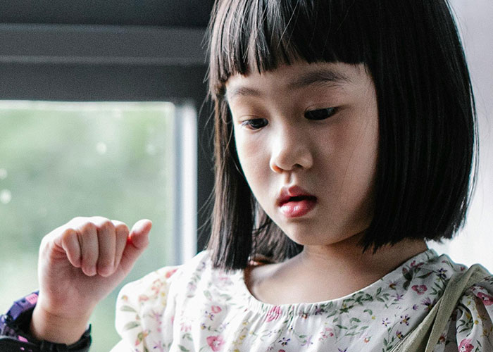 Young girl examining a fascinating item found inside the walls of her home with focused curiosity by a window.