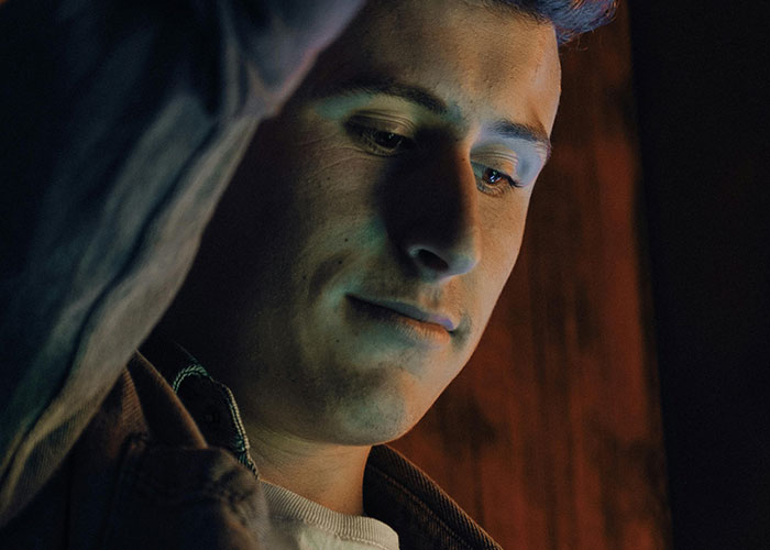 Young man looking down with an intrigued expression, immersed in bizarre events that creep people out stories.