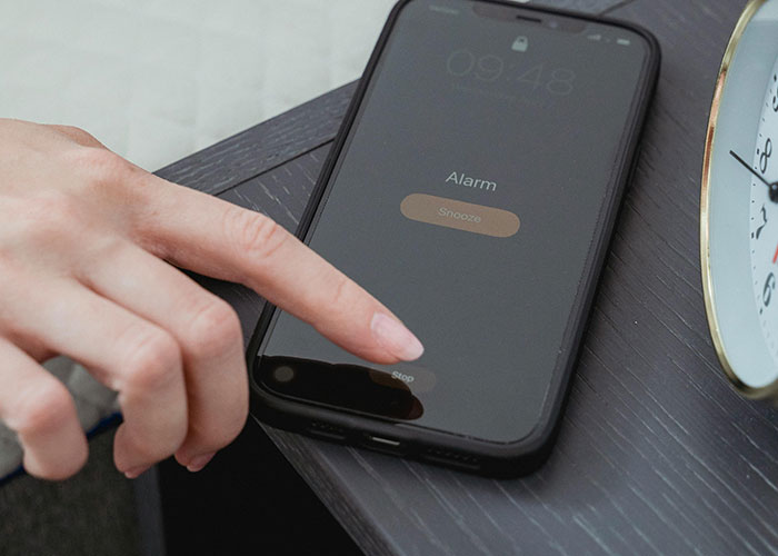 Person using a smartphone alarm to stop it while sharing life hacks that they can't believe others don't use.