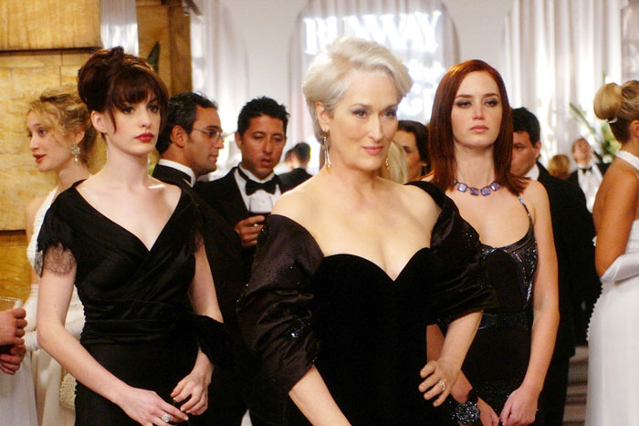 Three women in elegant black dresses at a formal event, illustrating millennial gray tones in modern movies.