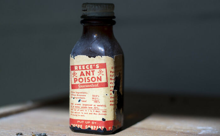 Old brown bottle of ant poison on a wooden surface, symbolizing heavy confessions and untold secrets.