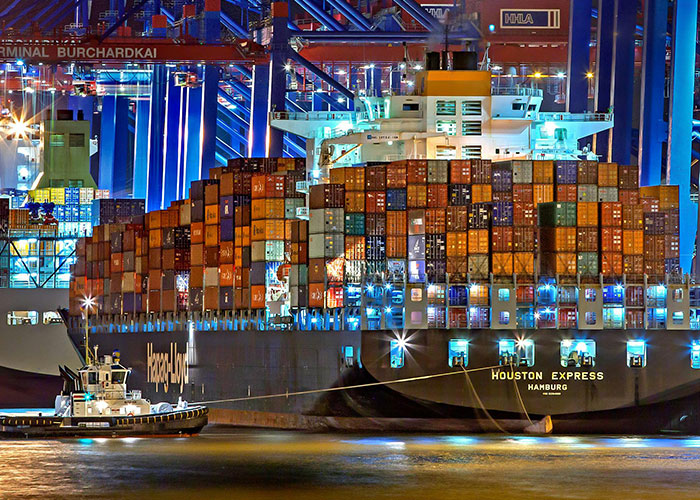 Container ship Houston Express docked at a busy port at night, illustrating common knowledge about global shipping logistics.