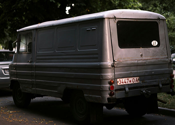 Old rusty gray van parked on a dim street, evoking eerie vibes in bizarre events that crept people out stories.