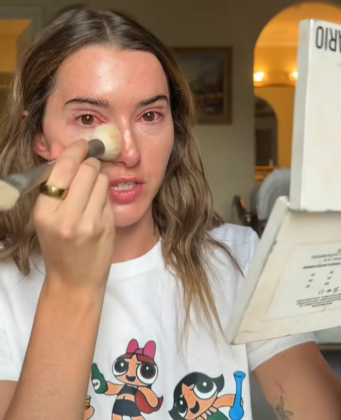 Influencer applying makeup indoors, criticized for partying while contagious, facing backlash for selfish and irresponsible behavior. Influencer applying makeup indoors, criticized for partying while contagious, facing backlash for selfish and irresponsible behavior.