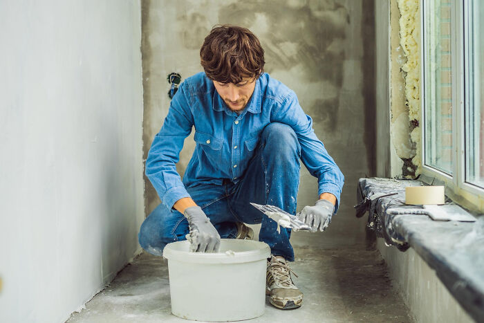 Young man in blue denim working on wall plaster, representing consequences of little lies that backfired hard.