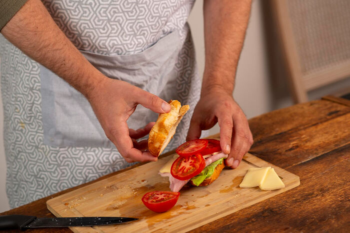 Clueless dad making a sandwich with tomato and ham while learning lovable things during pregnancy.