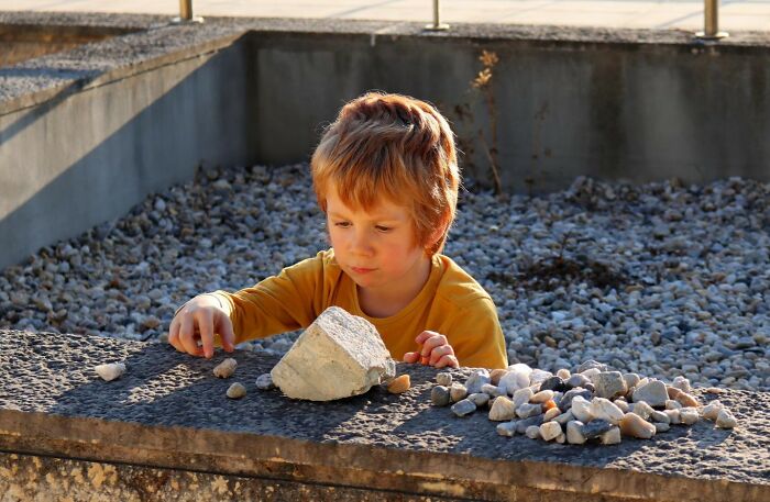 Young child playing with rocks outdoors, highlighting insider experiences shared by nepo babies in unique settings.