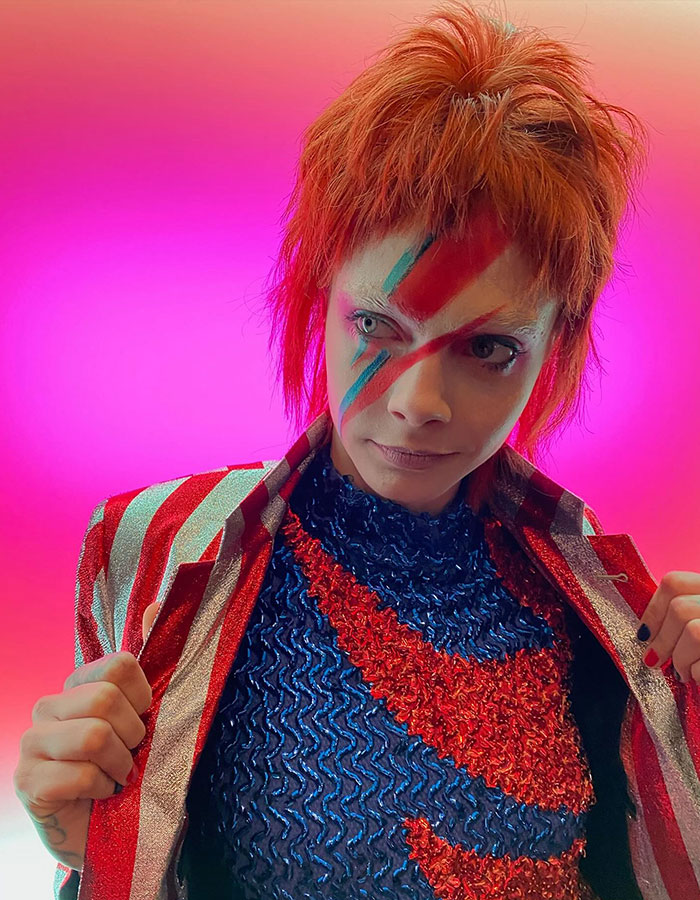 Celebrity in vibrant Halloween costume with painted face and striking red hair, showcasing creative Halloween costumes style.