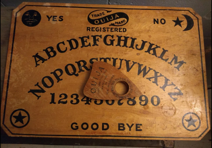 Vintage Ouija board on wooden surface, a popular scary game to play with friends in real life gatherings.