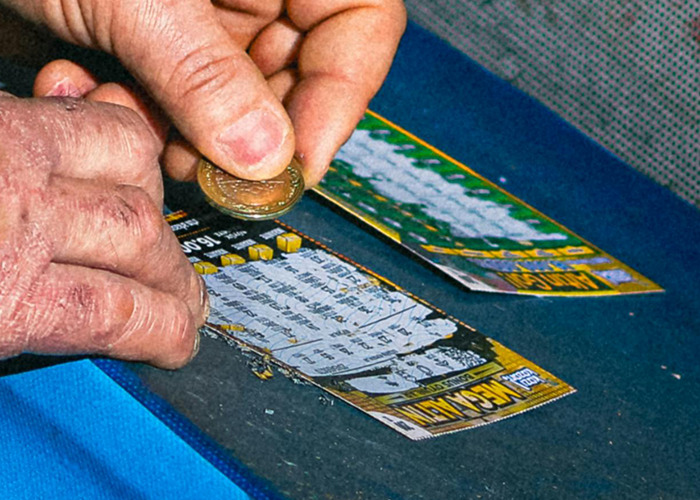 Hands scratching off lottery tickets, illustrating one of the absolute horrible gifts people have actually received.