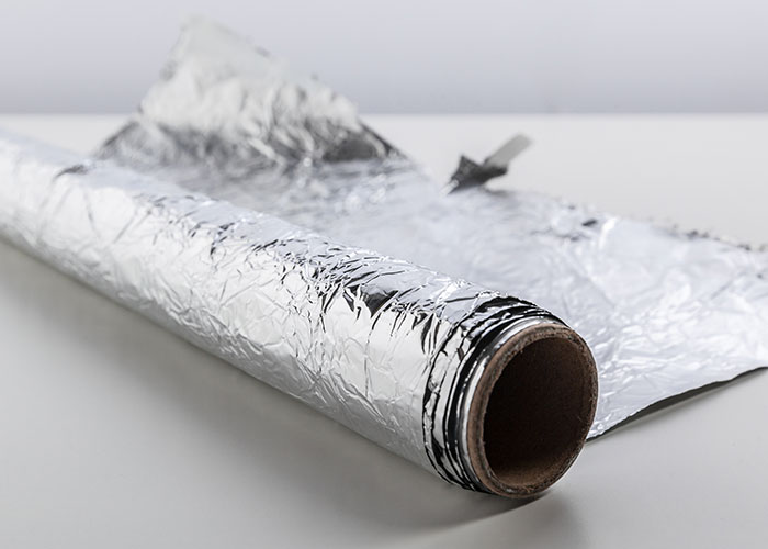 Roll of aluminum foil on a white surface representing a genius cleaning hack inspired by laziness for easy household use.