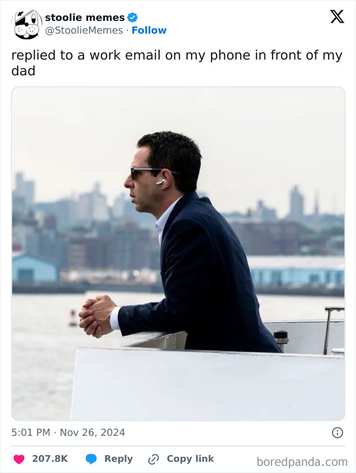 Man in business attire checking phone outdoors, illustrating relatable moments of having a job from popular tweets.