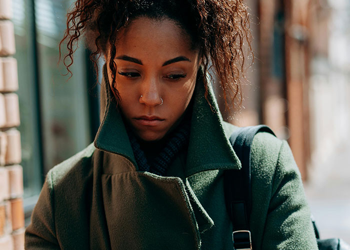 Woman with a green coat looking worried outdoors, capturing the eerie feeling of bizarre events that creep people out.