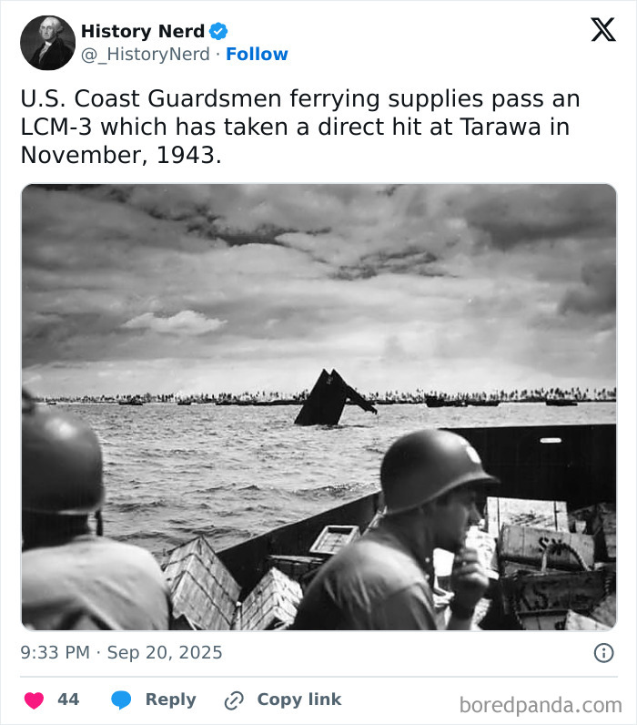 U.S. Coast Guardsmen ferrying supplies near a damaged landing craft during a historical World War II event.