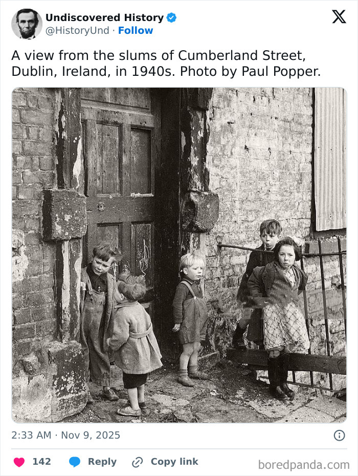Children playing outside a worn brick building in 1940s Dublin, capturing a fascinating moment lost to time.