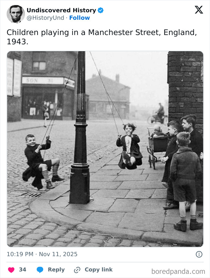 Children playing on swings tied to a lamppost on a Manchester street, a fascinating photo revealing moments lost to time.