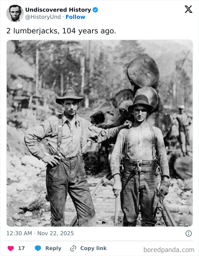 Two lumberjacks posing on railway tracks in a black and white photo revealing moments lost to time.
