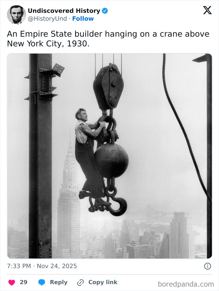 Empire State builder hanging from crane hook above New York City skyline in a historical moment lost to time.