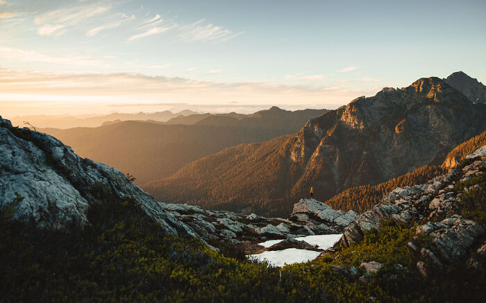 Person standing on a rocky mountain at sunrise, reflecting on finding purpose through a personal journey.