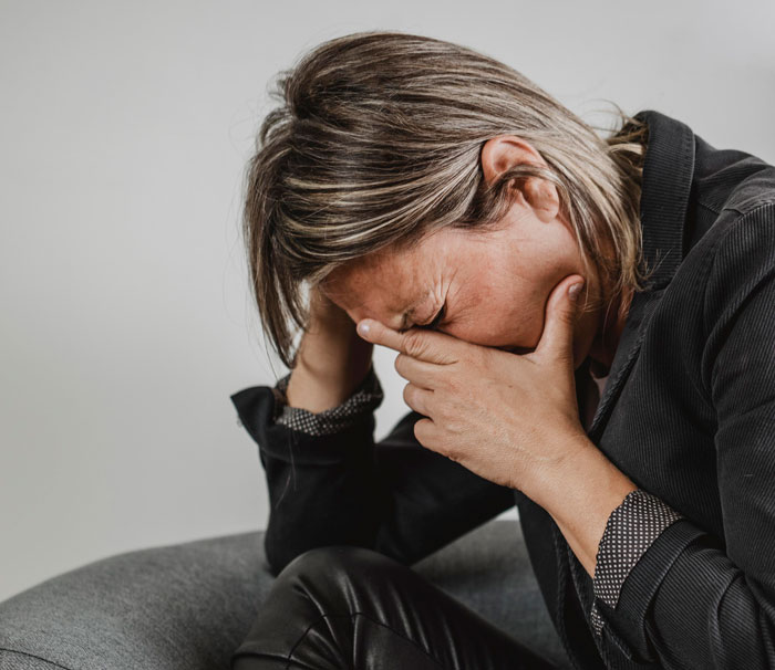 Woman overwhelmed with emotions sitting on a couch, illustrating MIL getting outplayed on vacation with the couple.