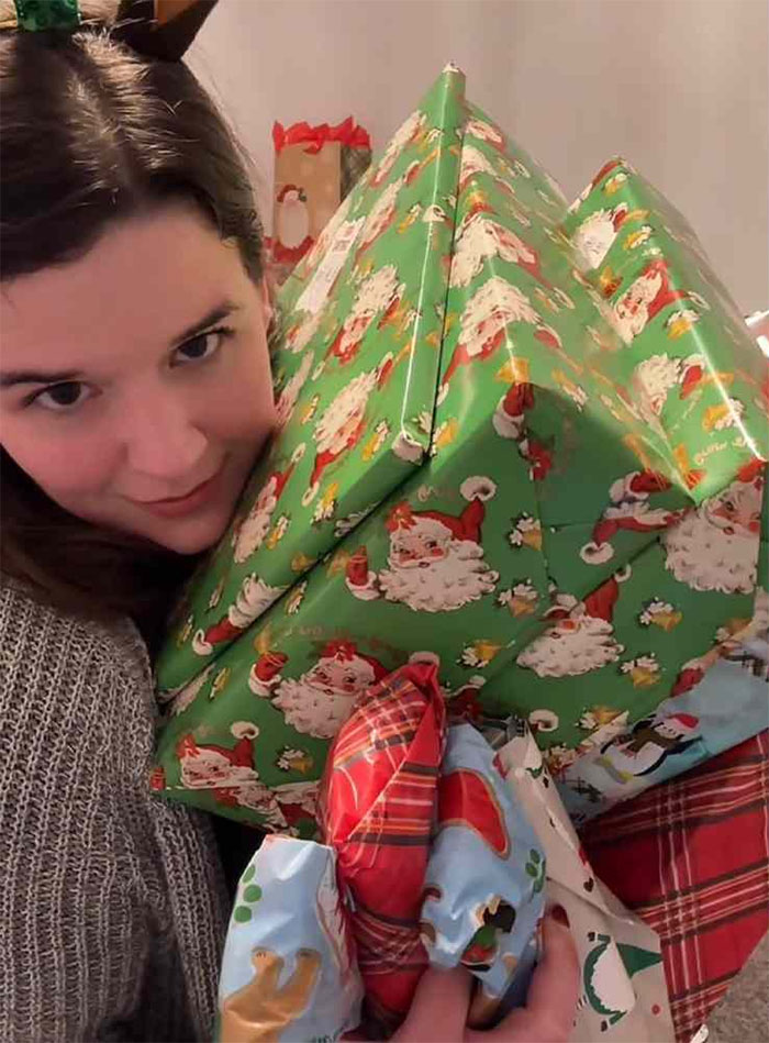 Mom holding a large stack of wrapped gifts for her kids, highlighting consumerism and gift giving for holidays.