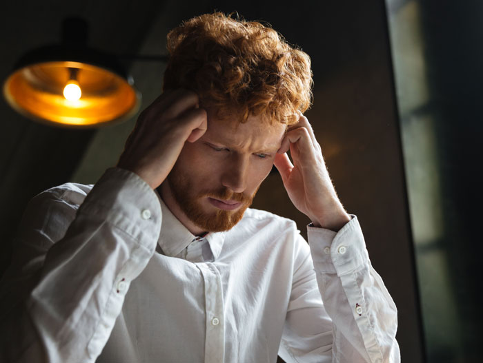 Stressed man holding his head, overwhelmed by the pressure of buying Thanksgiving items for the holiday.