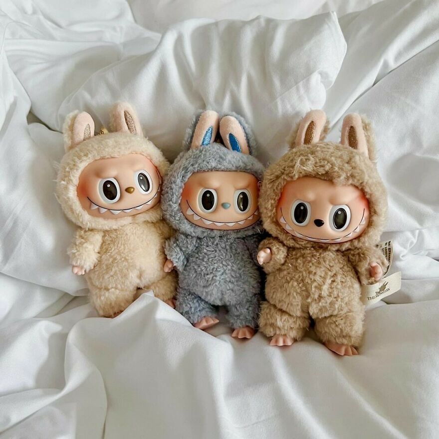 Three original Labubu dolls with furry bunny costumes sitting on a white fabric background, showcasing unique toy design.