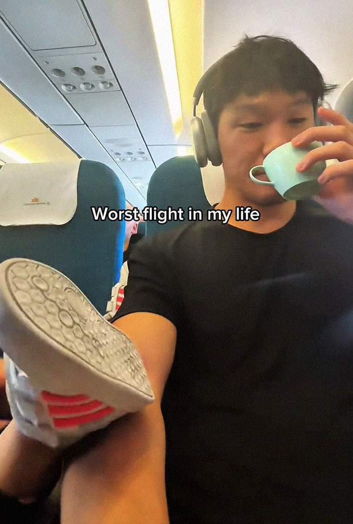 Frequent traveler on a flight showing frustration as a child's shoe is pressed against his arm inside an airplane cabin.