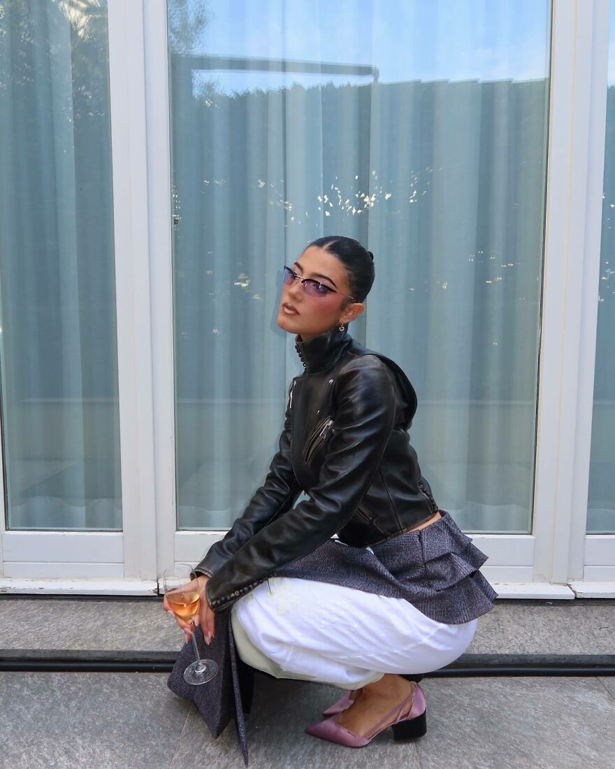 Charli D&rsquo;amelio wearing a leather jacket and sunglasses, holding a glass of wine, showcasing teen queen of cash style.