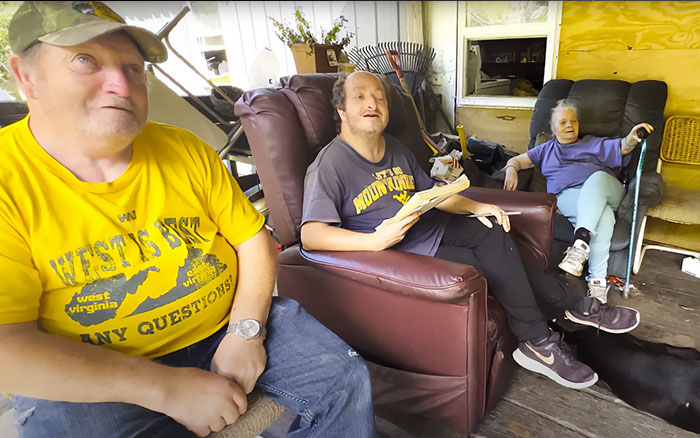 Three family members sitting in a cluttered room, part of America's most inbred family featured in viral internet reaction.