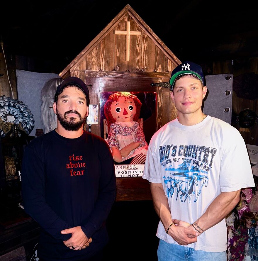 Matt Rife standing beside a man and the famous Annabelle doll inside a wooden case in a dimly lit room. Matt Rife standing beside a man and the famous Annabelle doll inside a wooden case in a dimly lit room.