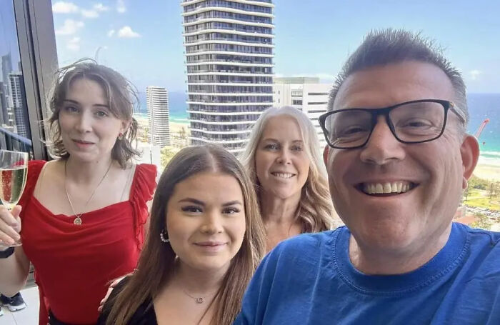 Politician smiling with family in city apartment with ocean view shortly before resignation news breaks.