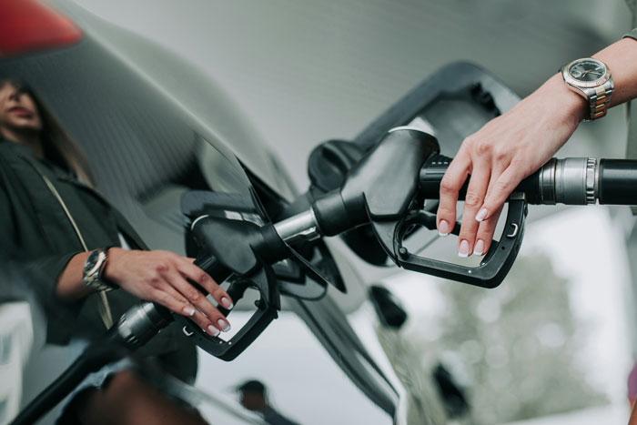 Woman refueling car at gas station, illustrating important girl code rules shared by women for strong friendships.