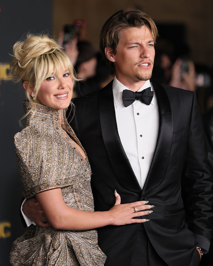 A couple dressed elegantly at a formal event, highlighting fans' reactions on Millie Bobby Brown legally changing her name.
