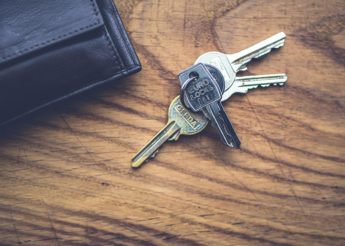 Set of keys and a black wallet on a wooden surface, illustrating practical life hacks people often share.