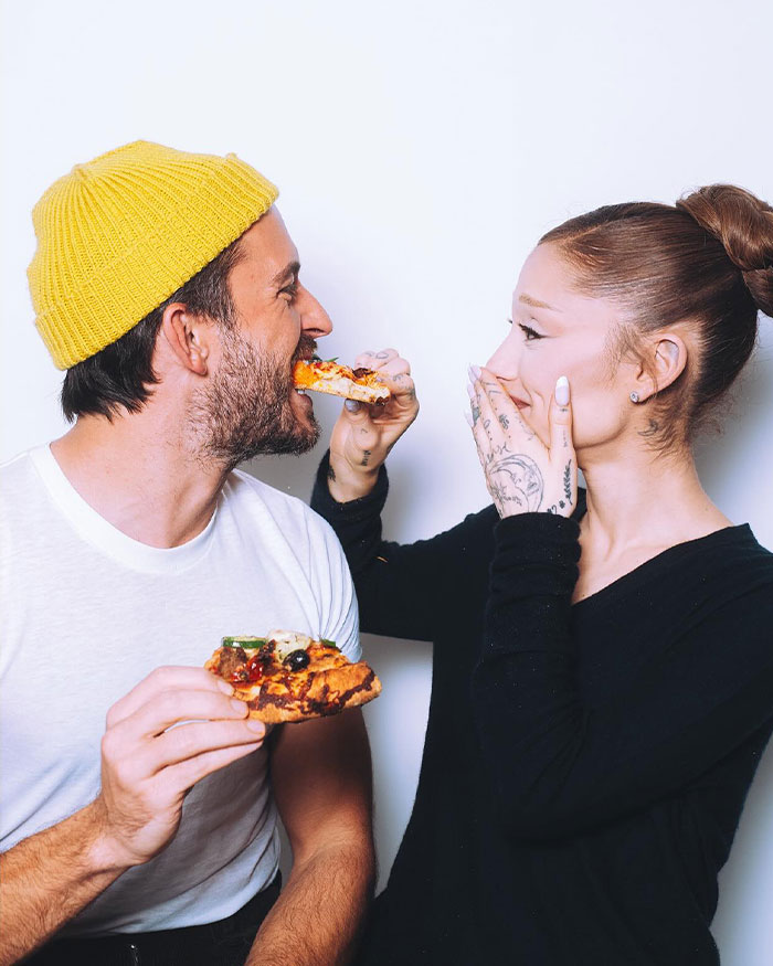 Ariana Grande and Jonathan Bailey share a playful moment eating pizza, sparking home wrecking roast discussions.