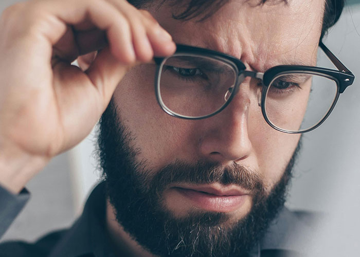 Man with glasses inspecting a wall closely, discovering fascinating items people found in the walls of their homes.